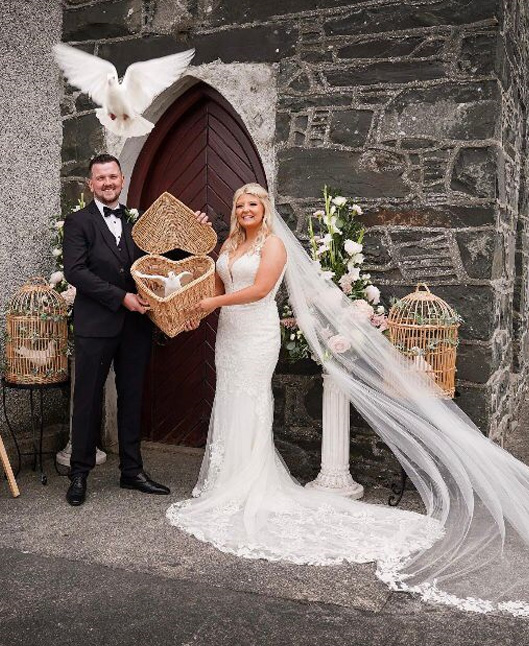 A wedding couple releasing a dove from a heart shaped basket.