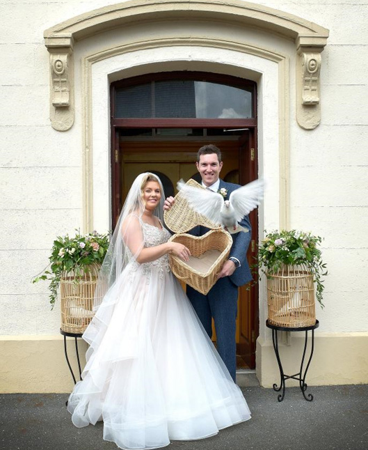 A wedding couple releasing a dove from a heart shaped basket.